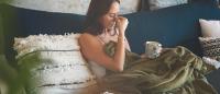 Shot of a young woman suffering from a headache and feeling sick on the sofa at home